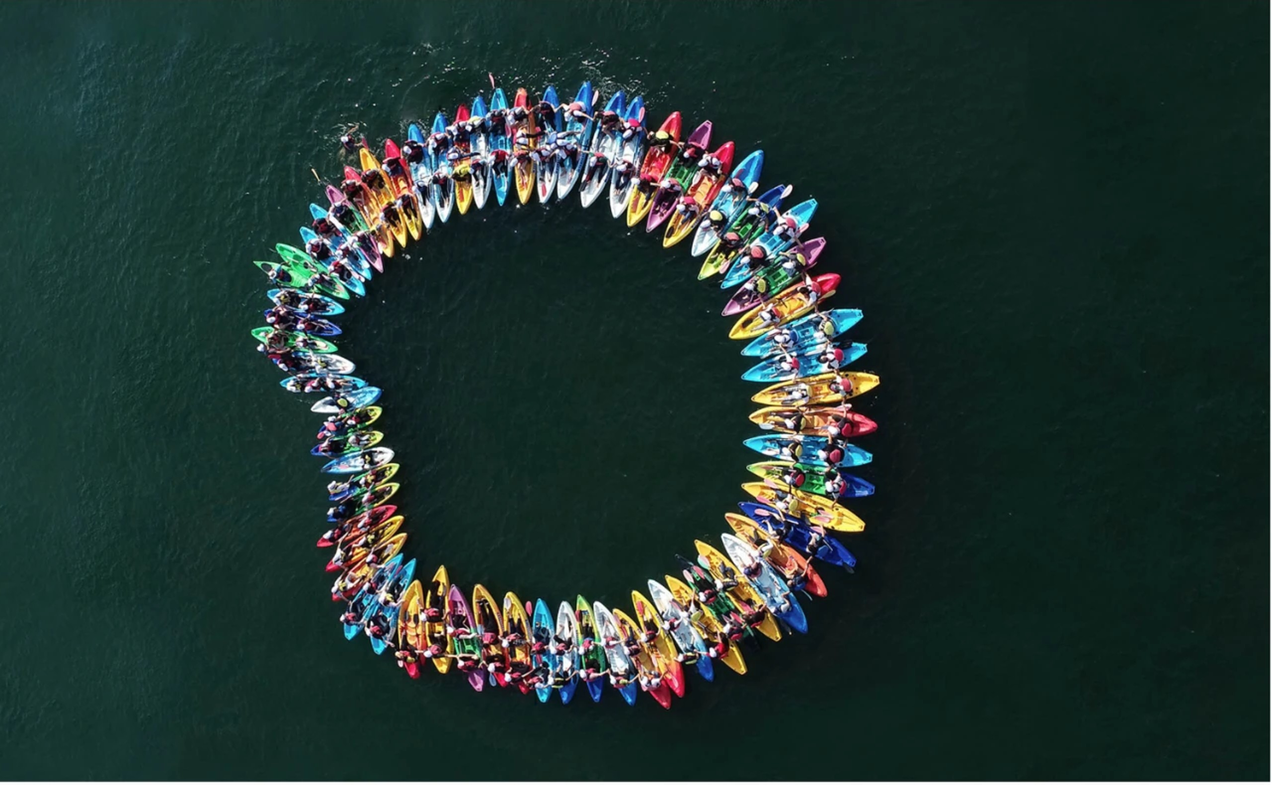 dasso team gathered in a circle of kayaks on a lake